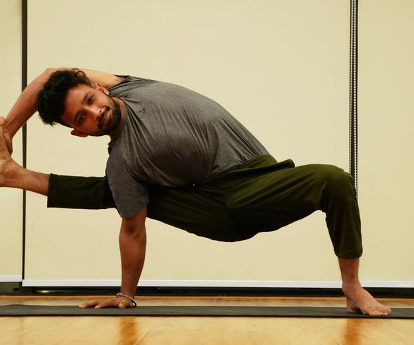 Man holding a calm yoga pose on a mat at sunset.